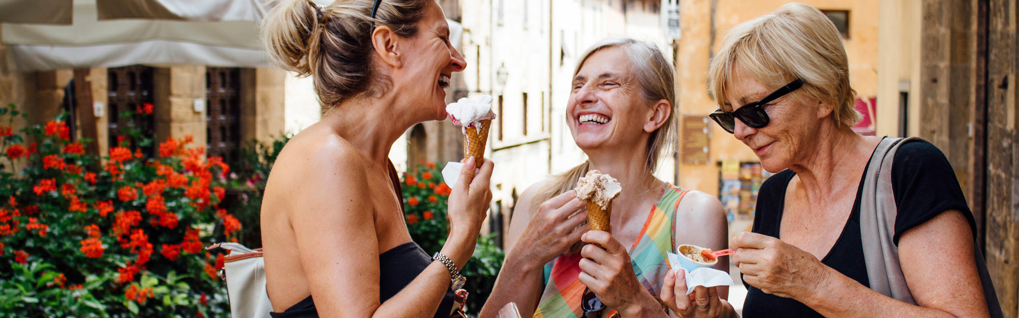 Tre glada äldre kvinnor äter glass i stan en sommardag